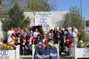 Team photo in front of the horse park, with horses in the background 
