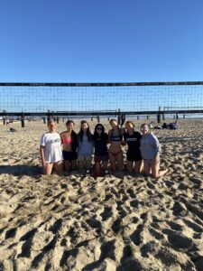People taking photo together at the beach in front of a volleyball net