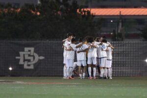 Team huddle at SDSU in white uniforms
