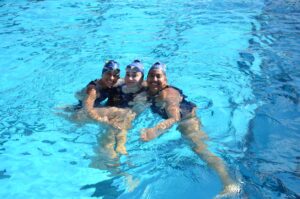 Three people smile in pool