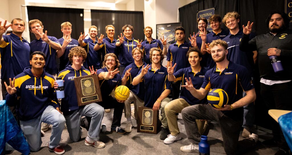 The UCSD men's club water polo team hold up three fingers as they hold their national championship trophy.