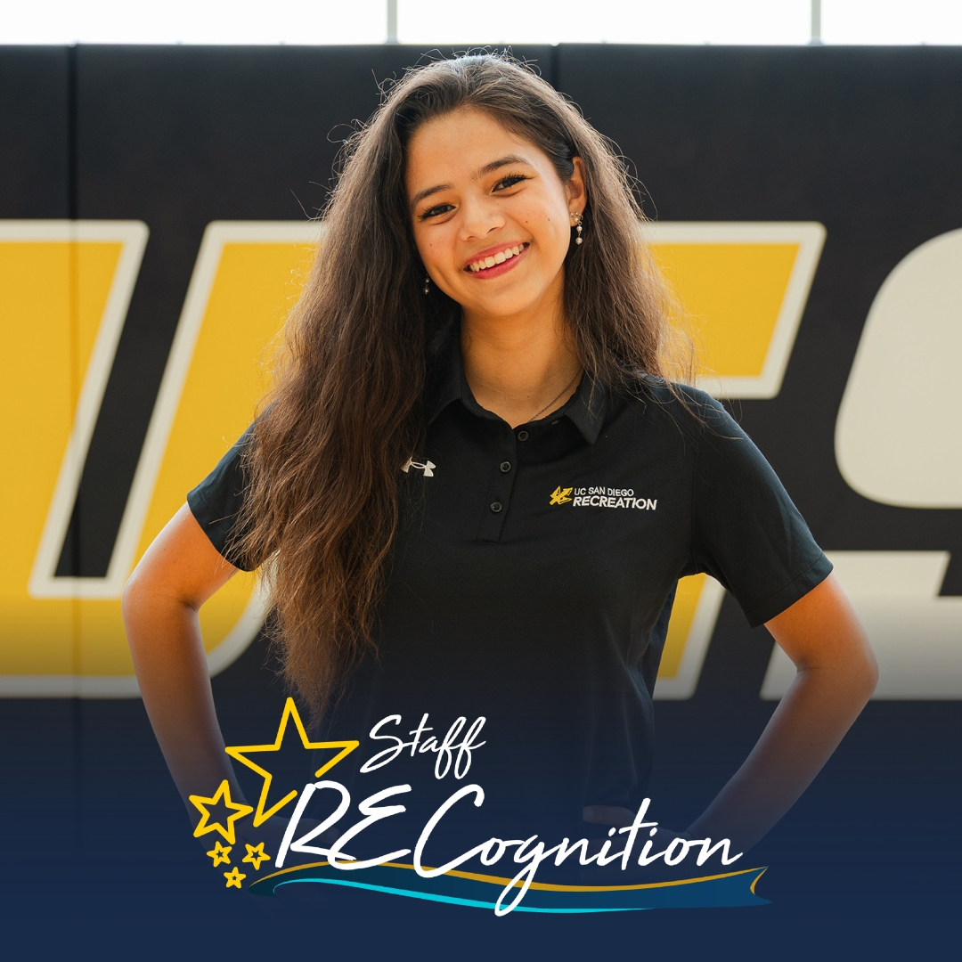Evalyn Perez wears a blue polo shirt in front of a blue wall with the logo of UC San Diego.