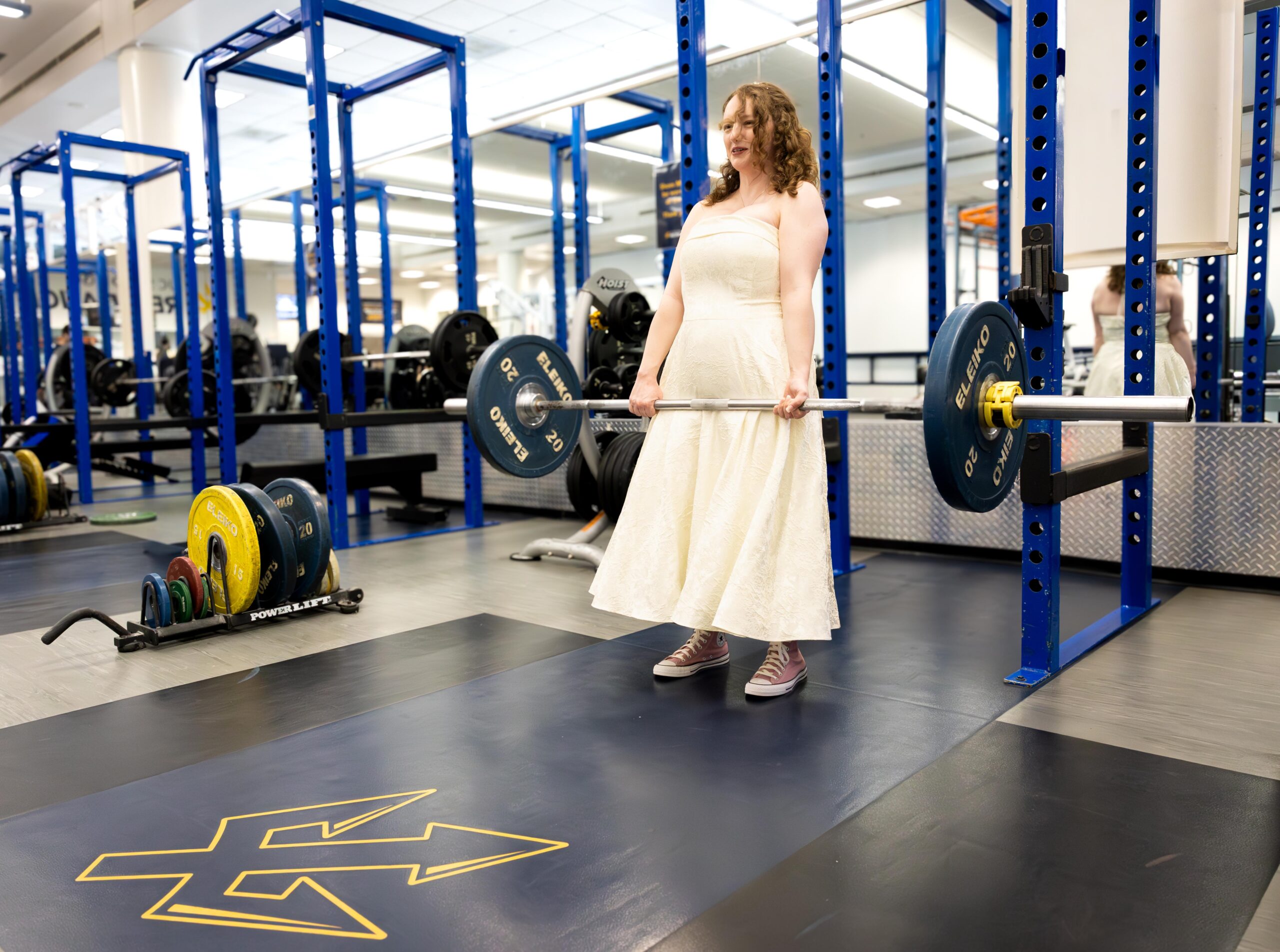 Sydney wears a wedding dress as she stands up this deadlift, shown in the UCSD weight room.