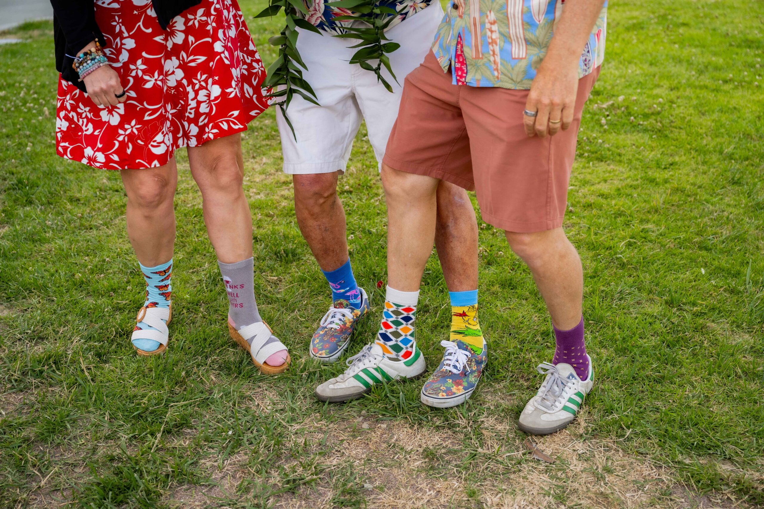 Three people show off their fancy colorful socks and shorts.