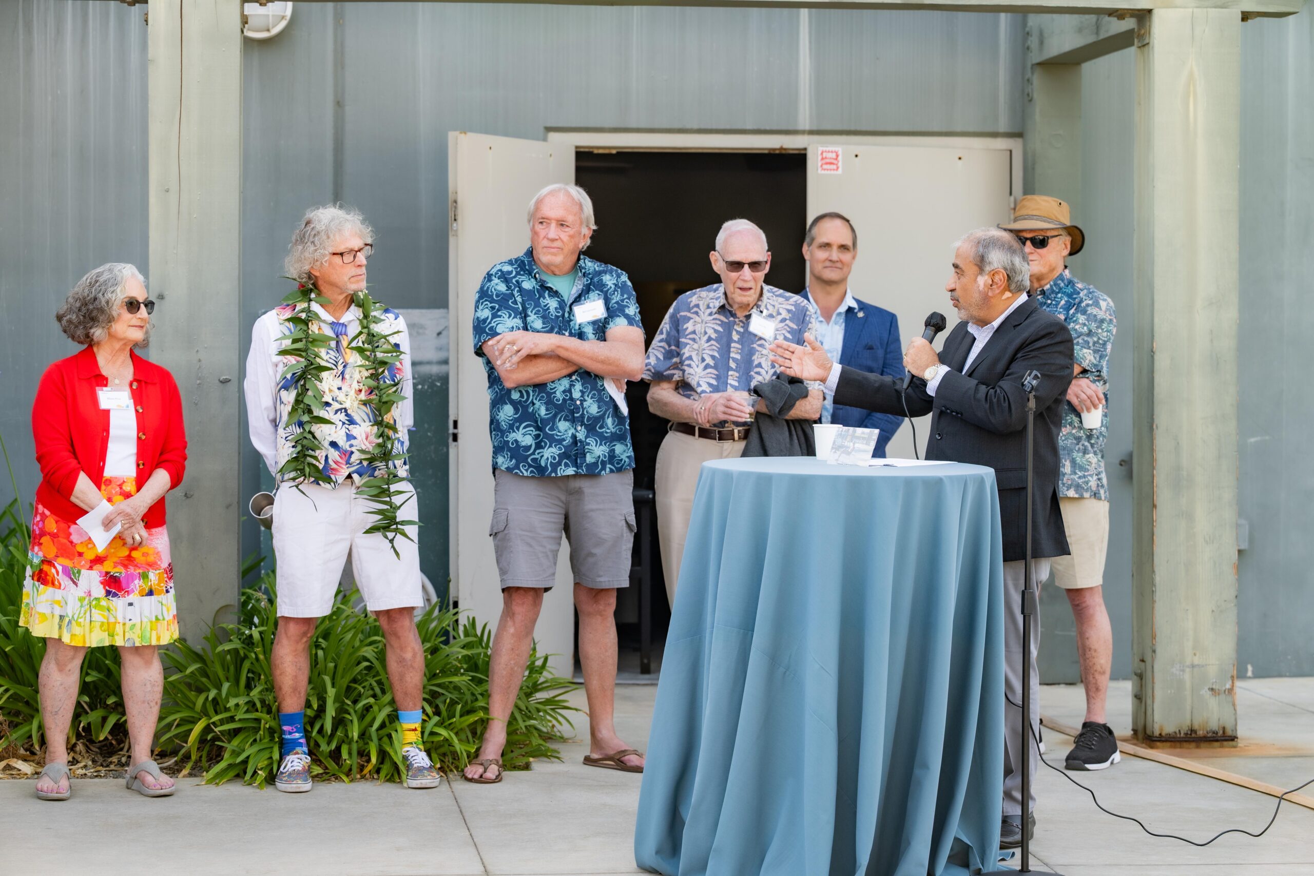UC San Diego Chancellor Pradeep Khosla wears a blazer as he speaks into a microphone in front of a handful of people.