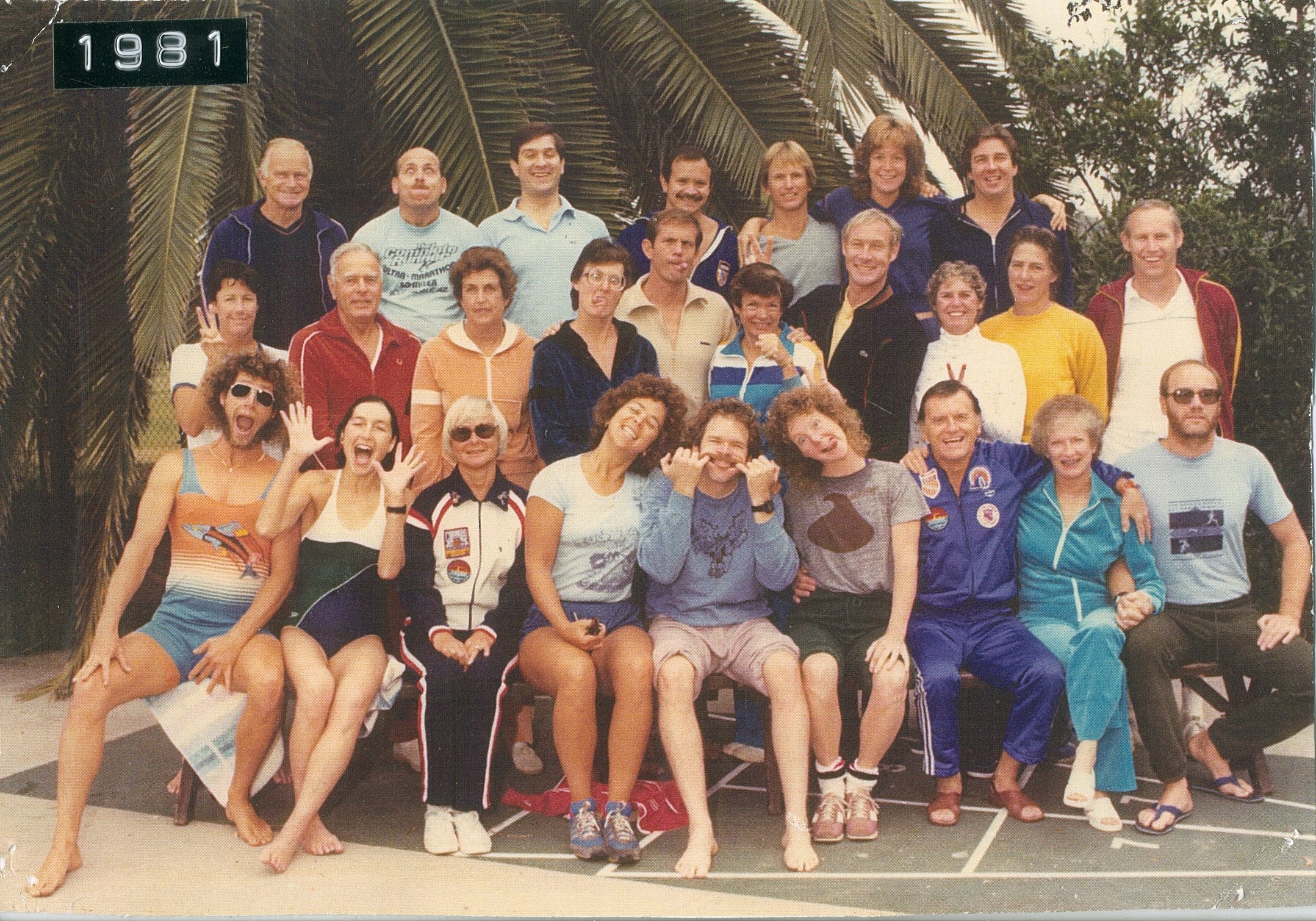 A sepia-toned group photo of almost 20 people, many making silly faces and smiling.