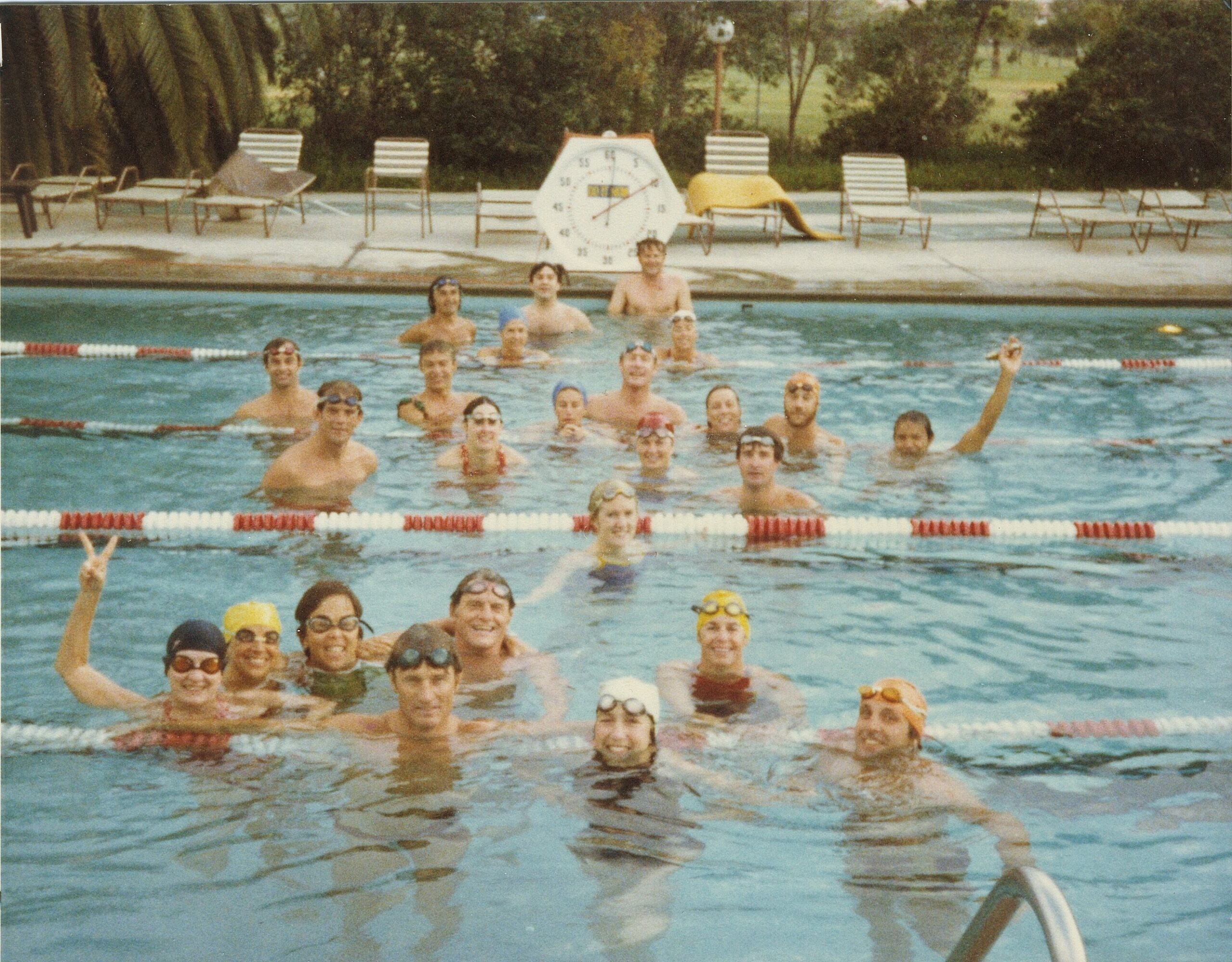 Almost 20 people tread water as they pose for a photo in a pool.